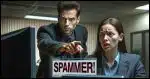 One person pointing accusingly at another person, saying 'SPAMMER!'. The scene is intense, with the accuser looking serious and somewhat angry, while the accused appears surprised and defensive. The background is a nondescript office setting.