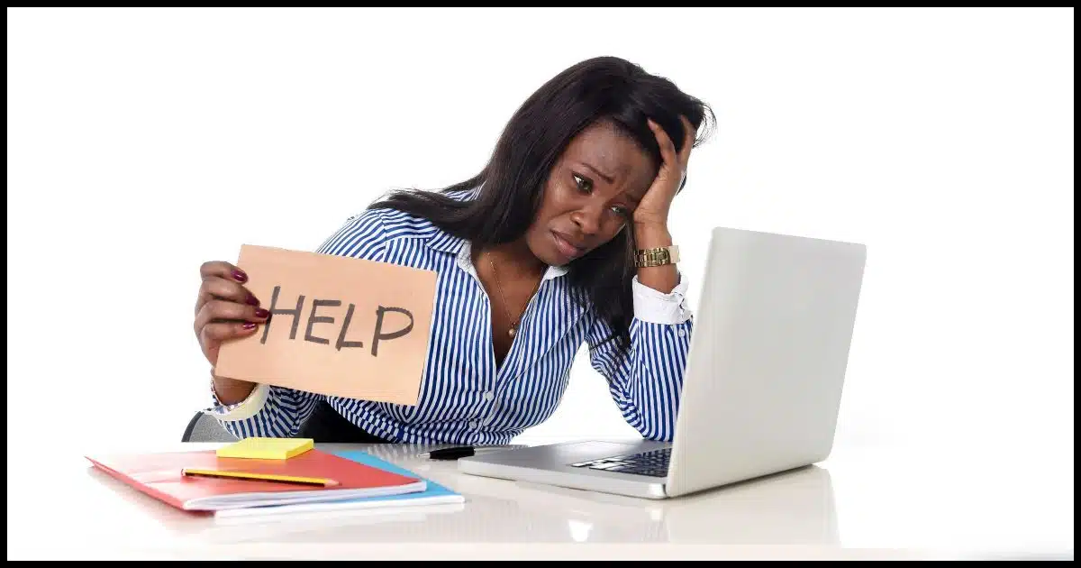 Person at computer holding a "Help" sign.