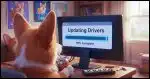 A Corgi sitting in front of a computer screen drinking from a can of "Caf Pow!". The screen says "Updating Drivers" with a progress bar.
